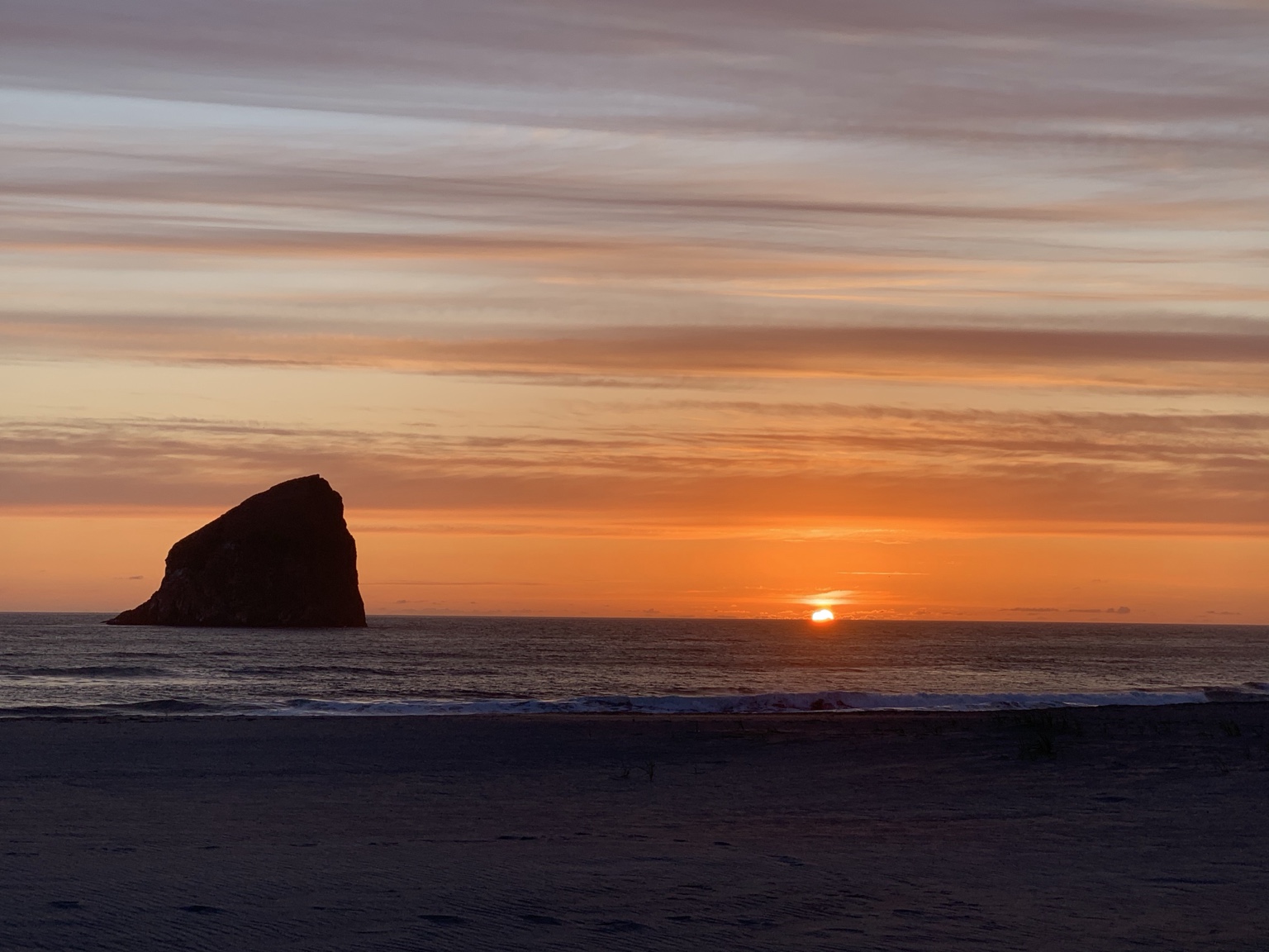 Sunset over the ocean beside a sea stack